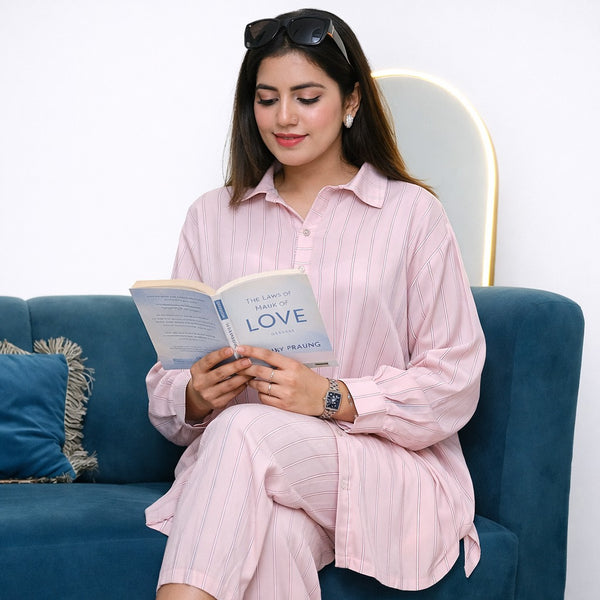 Woman in pink outfit reading a book titled 'LOVE' on a blue couch.