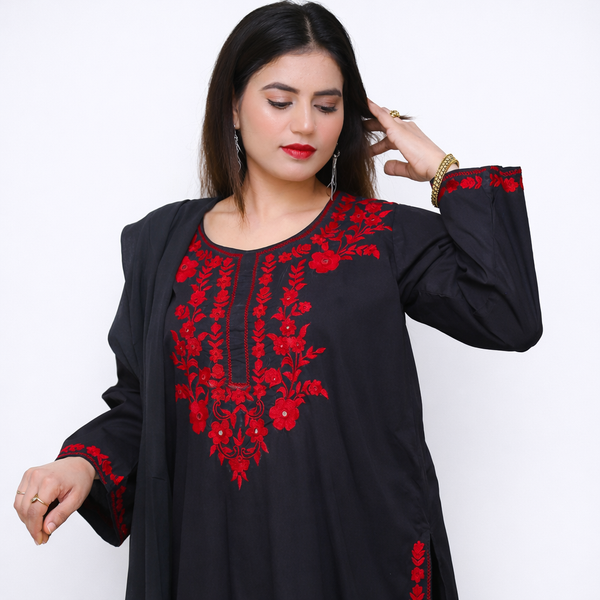 Woman wearing a black top with red floral embroidery on a white background