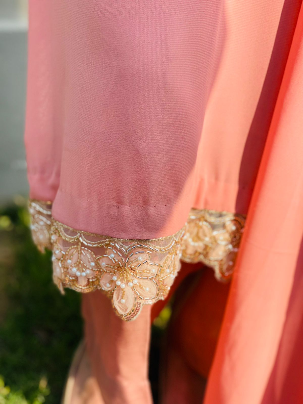 Close-up of a pink garment with lace trim against a blurred green background