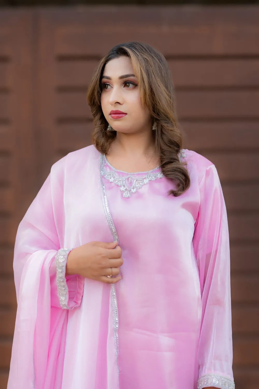 Woman wearing a pink traditional outfit with a brown background