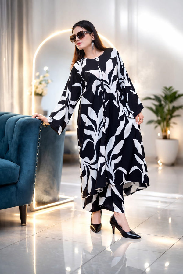 Woman in a black and white patterned dress standing in a modern interior setting.