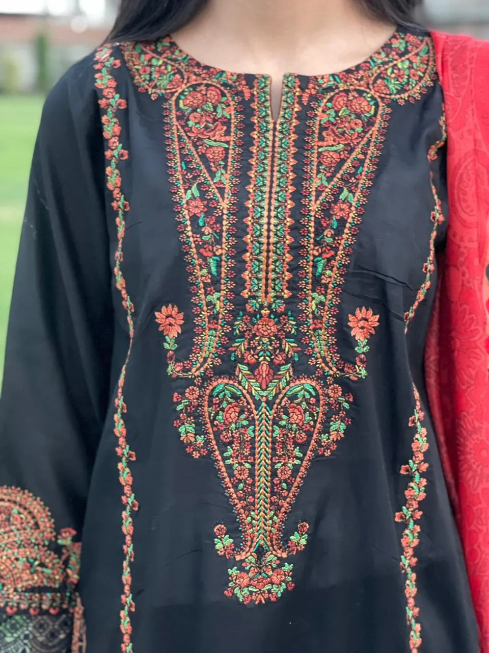 Black embroidered garment with red and green patterns
