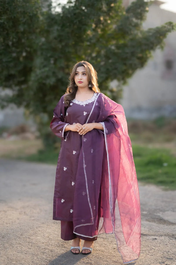 Woman in a traditional outfit with a pink dupatta standing outdoors.