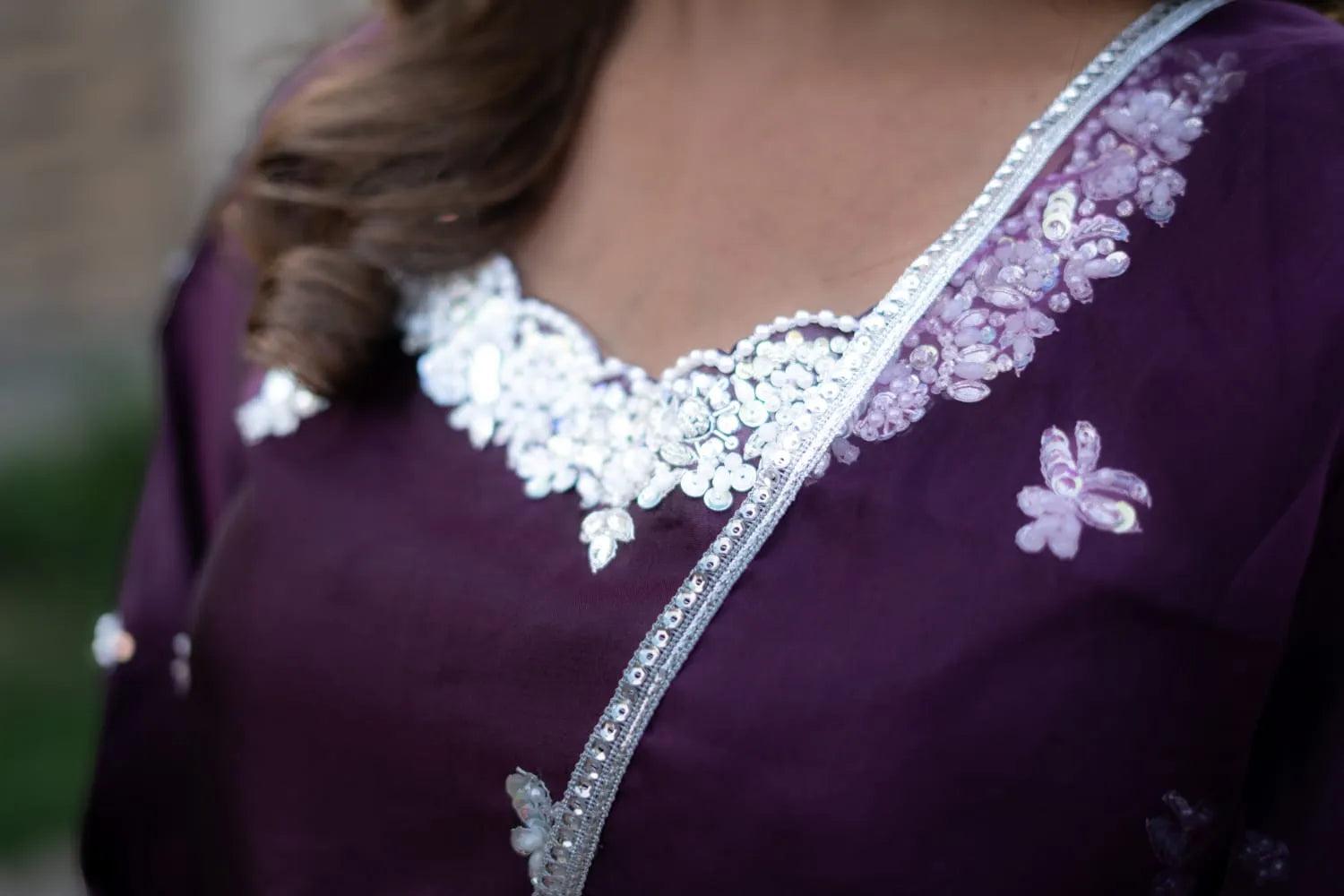 Close-up of a purple garment with white floral embroidery