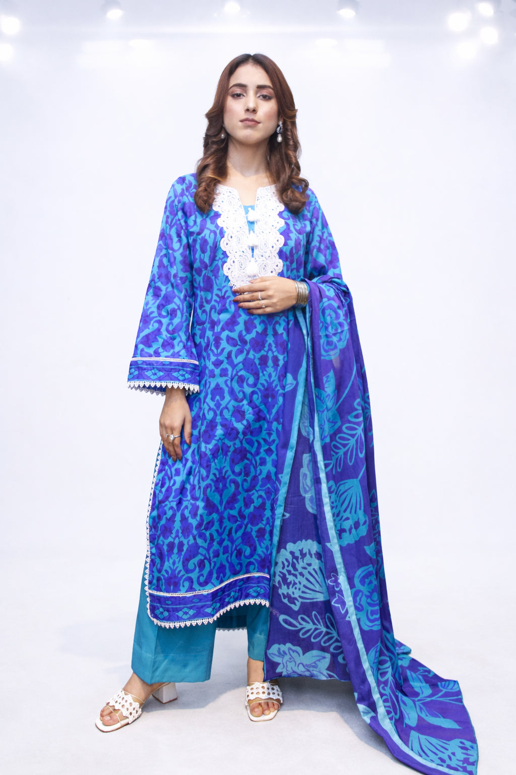 Woman wearing a blue patterned outfit with a matching dupatta on a white background