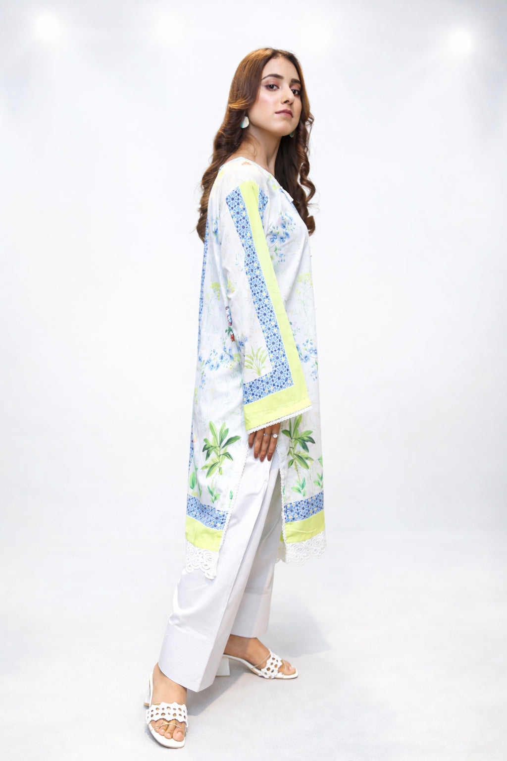 Woman wearing a white outfit with blue and yellow patterns on a white background