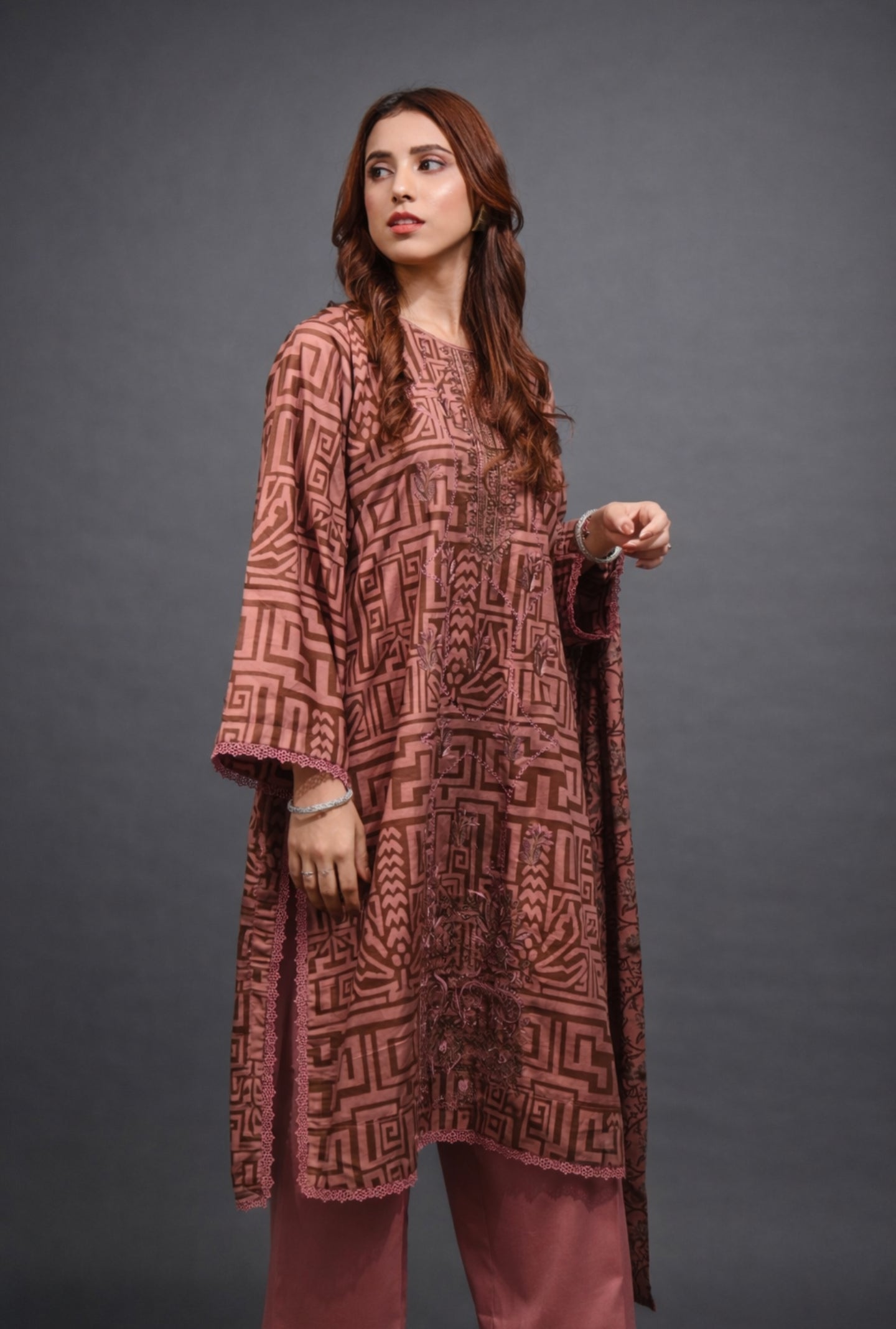 Woman wearing a patterned maroon outfit against a gray background
