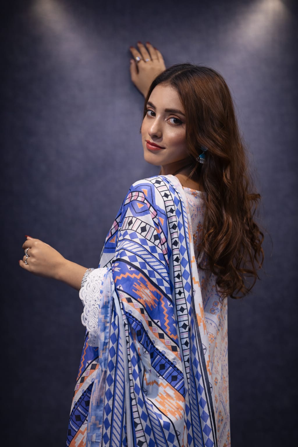 Woman wearing a blue and white patterned dress against a dark background