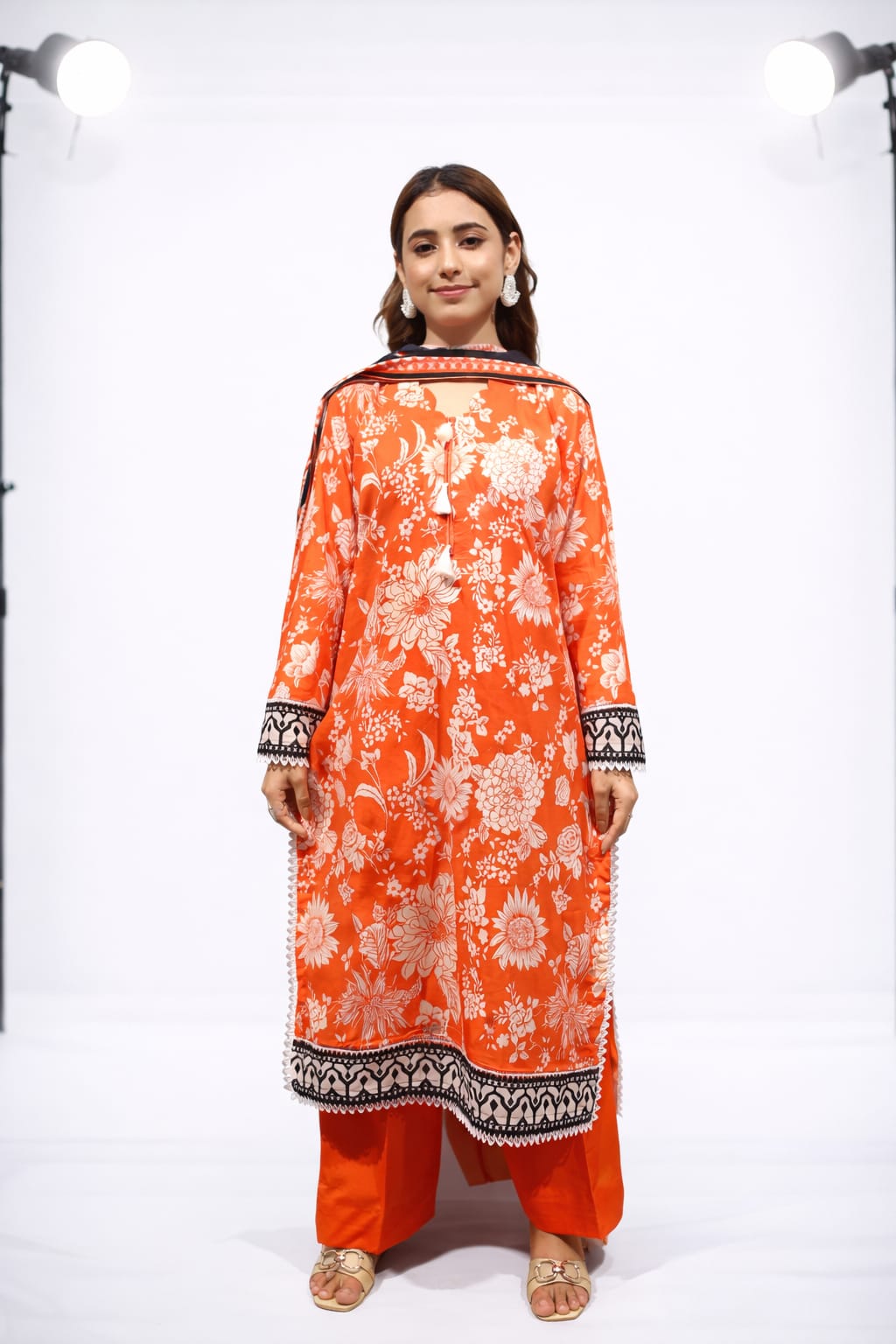 Woman wearing an orange floral dress with a white background