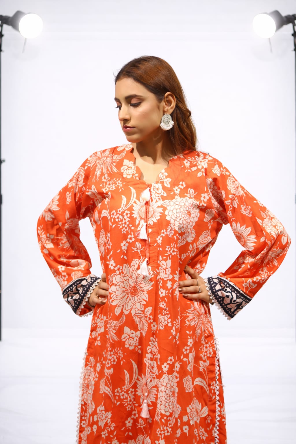 Woman wearing an orange floral dress with a white background