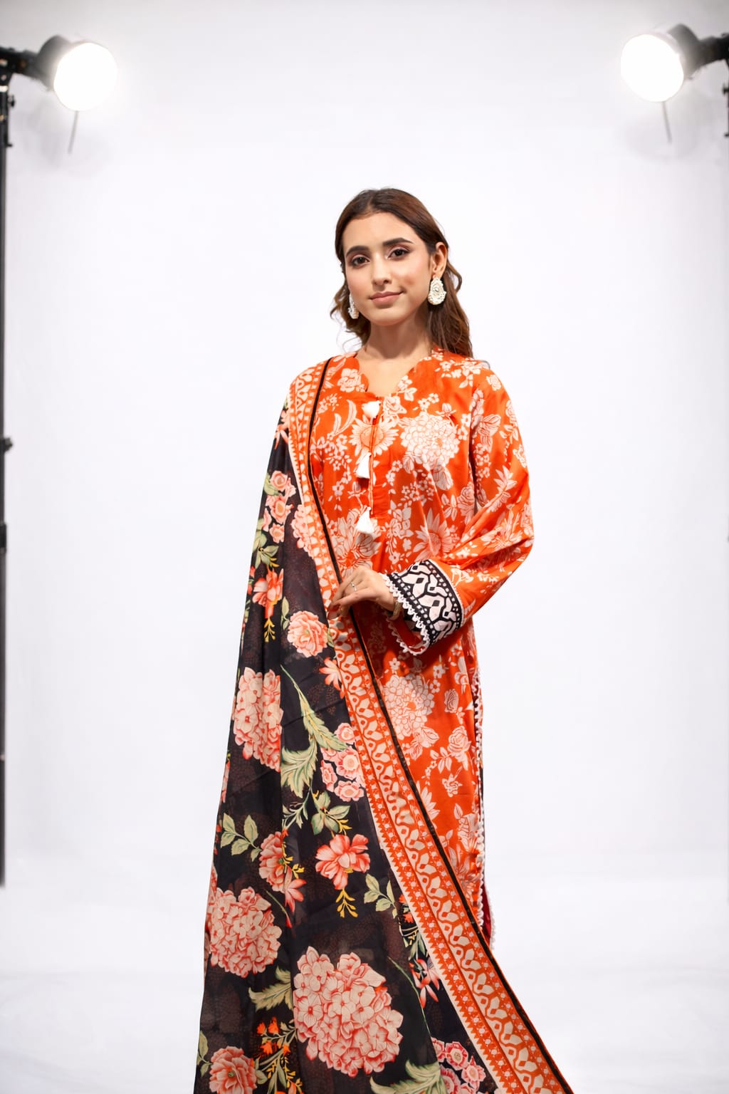 Woman wearing a floral dress with a black and orange pattern on a white background