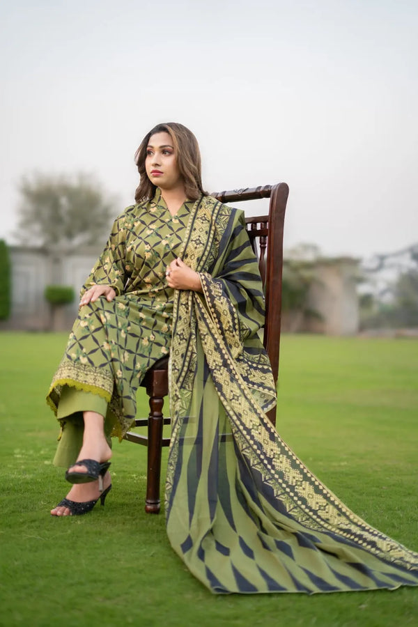 Woman sitting on a chair wearing a green and blue patterned saree in an outdoor setting.