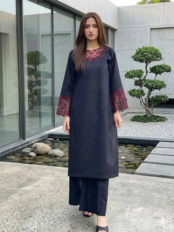 Woman wearing a dark blue traditional outfit with red embroidery in an outdoor setting.