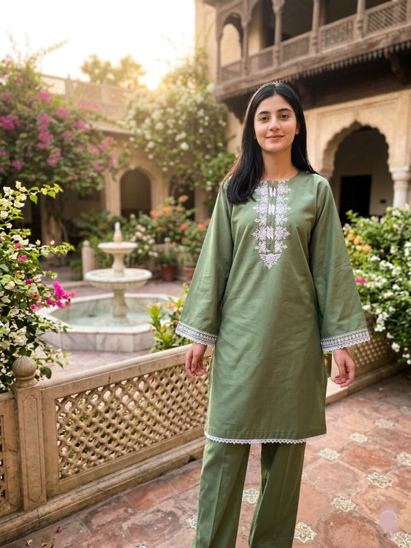 Woman in a green traditional outfit standing in a courtyard with floral decorations.
