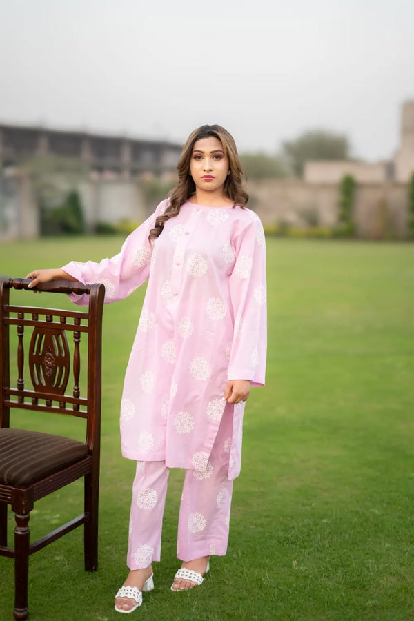 Woman in a pink traditional outfit standing on grass with a blurred background