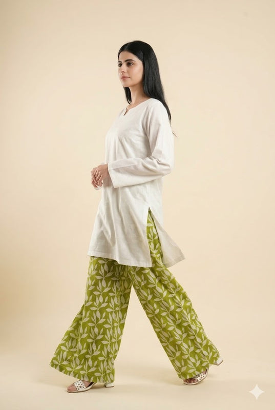 Woman wearing a white top and green patterned pants on a beige background