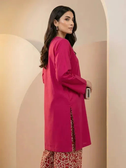 Woman wearing a bright pink kurta with a beige background