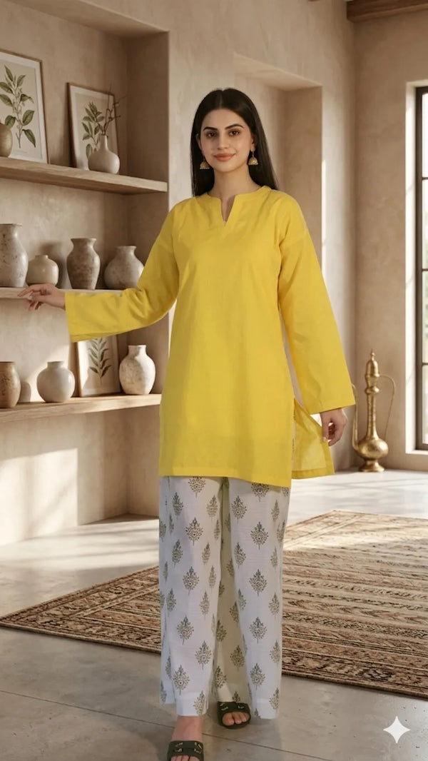 Woman wearing a yellow kurta with white pants in a room with shelves and decor.
