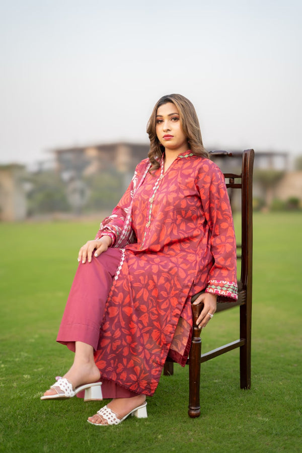 Woman in a red patterned outfit sitting on a chair outdoors.