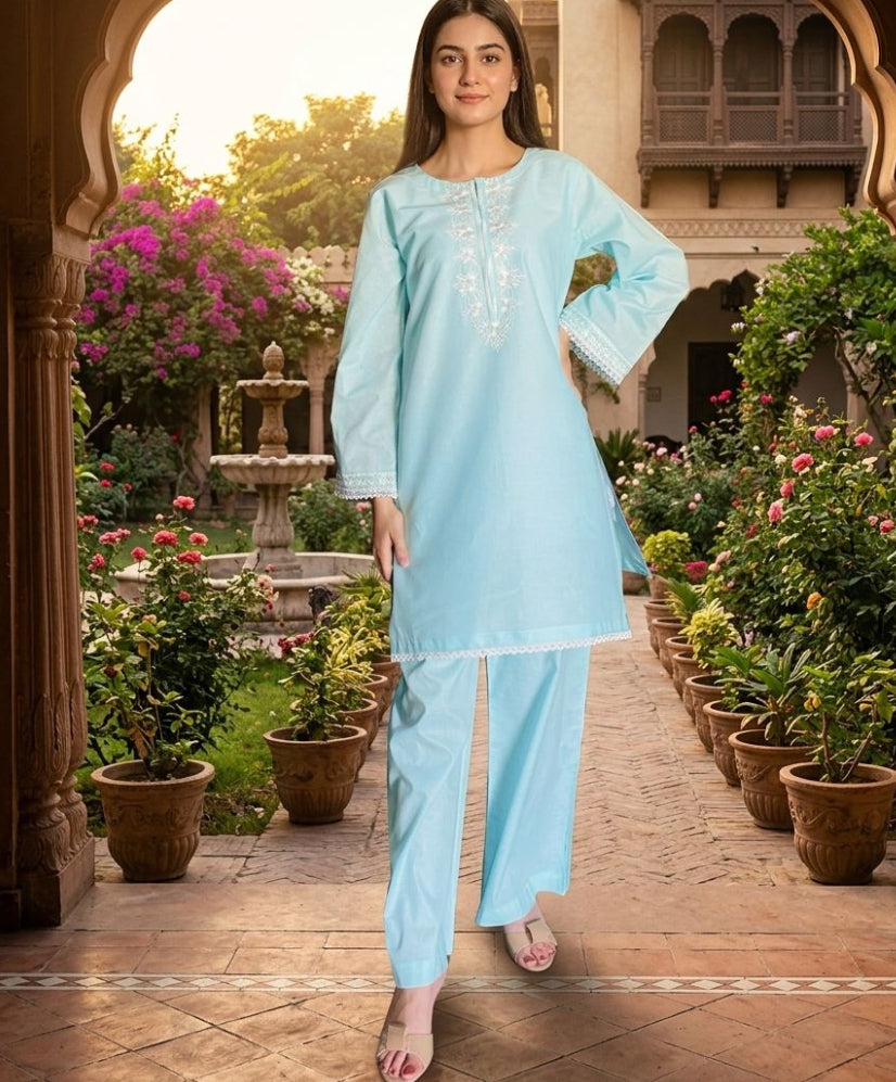 Woman in a light blue traditional outfit standing in a garden with arches and plants.