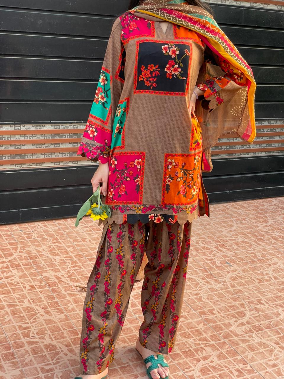Person wearing a colorful traditional outfit with floral patterns on a tiled floor.
