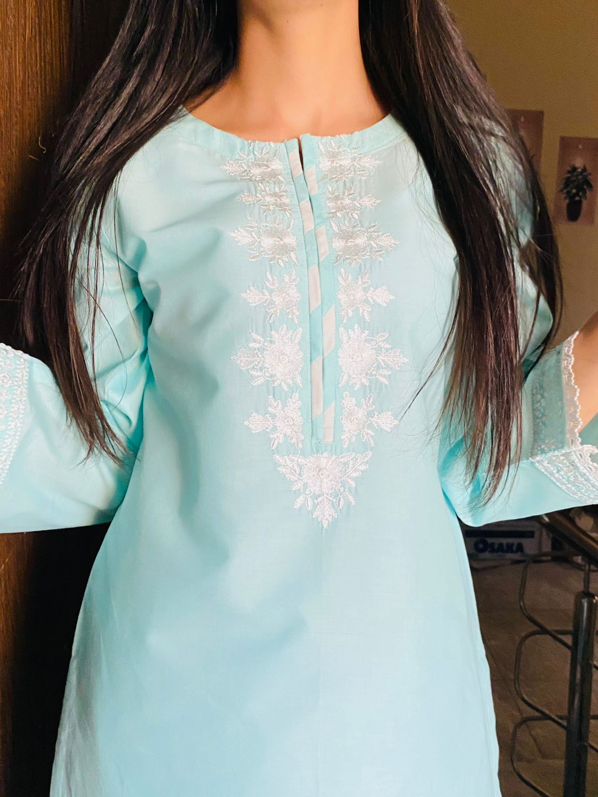 Light blue embroidered top worn by a person indoors